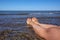 Woman is resting on the sea concept. Woman legs on sandy beach with water waves for healthy lifestyle design. Beauty, spa concept.