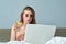 Woman resting sitting in bed looking at laptop computer, drinking water with lemon