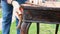 A woman restores old furniture in the fresh air. Vintage table. Wearing rubber gloves