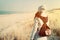 Woman with retro backpack on the beach looking at the sea