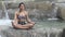 Woman in retro swimsuit doing yoga in a waterfall