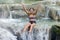 Woman in retro swimsuit playful in a waterfall