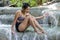 Woman in retro swimsuit sitting in a waterfall