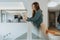 Woman reviewing paperwork while leaning on a glass fence at the office hallway.