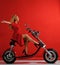 Woman ride new electric car motorcycle bicycle scooter with hands spread freedom sign laughing smiling on red background