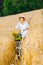 Woman rides cycle with apples and flowers in rye field