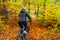 Woman riding bicycle in city forest in autumnal scenery