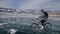 Woman is riding bicycle on the ice. The girl is dressed in a silvery down jacket, cycling backpack and helmet. Ice of