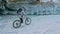 Woman is riding bicycle near the ice grotto. The rock with ice c