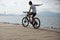 woman riding a bike on sunny seaside with arms outstretched