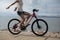 woman riding a bike on sunny seaside with arms outstretched