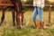 Woman with riding boots standing on pasture with horse