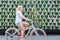 Woman riding bycicle by green urban vertical garden wall.