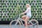 Woman riding bycicle by green urban vertical garden wall.