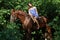 Woman riding horse bareback through forest