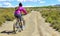 Woman riding a mountain bike by a muddy path of dirt