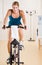 Woman riding stationary bicycle in health club