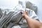 Woman right hand picking up white crumpled bed sheet on white bed, Close up shot, Selective focus, Bedroom cleaning concept