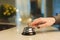 Woman ringing hotel reception service bell closeup