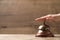 Woman ringing hotel service bell at wooden table, closeup. Space for text