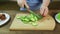 Woman rings cucumber on a wooden board for salad