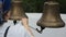 Woman rings in temple bells pulling rope that she keeps in her right hand.