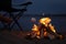 Woman roasting marshmallow over burning firewood on beach, closeup