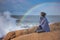 Woman On rocky Beach, rainbow over the stormy sea