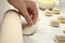 Woman with rolling pin cooking delicious dumplings at table