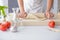 Woman rolling pizza dough using rolling pin.