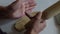 A woman rolls a dough on a table surface with a wooden rolling pin