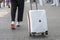 A woman rolls a white suitcase on wheels, close-up. Concept: hand Luggage on trips and trips, things on the road, going on vacatio