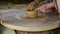 Woman rotates wheel by foot potter makes next clay pot
