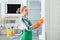 Woman in rubber gloves cleaning empty refrigerator