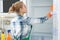 Woman in rubber gloves cleaning empty refrigerator