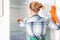 Woman in rubber gloves cleaning empty refrigerator