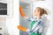 Woman in rubber gloves cleaning empty refrigerator