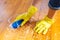 Woman in rubber gloves is using floor brush to cleaning floor