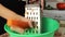 A woman rubs fresh carrots on a grater into a Cup in the kitchen.