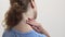 Woman rubs sore neck with hand on white background, back view, closeup. Woman stretches her neck and massages it