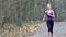 Woman runner is jogging on forest path in park.