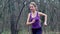 Woman runner is jogging on forest path in park.