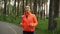 Woman runner training in rainy city park in the morning. Sportive fitness female jogging alone in parkland surrounded by green tre