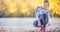 Woman runner tying shoelaces before jogging in autumn tree alley park. Sports female autumn outfit leggings and thermal underwear