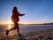 Woman running along shore of a frozen lake in winter spring