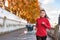 Woman running in autumn fall outdoor city street. Female runner training outdoor in profile. Healthy lifestyle image of