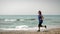 Woman running on beach. Female exercising with outdoor running on seashore. Girl doing fitness cardio exercises outdoors. Sport ac