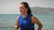 Woman running on beach at summer sunny day. Fit athletic female jogging on seashore in the morning, doing cardio fitness exercises