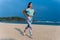 Woman running on beach at sunset. Beautiful fitness caucasian girl exercising outdoors on sea background. Caucasian fit