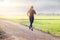 Woman running excercise on rural road of green field sunset back